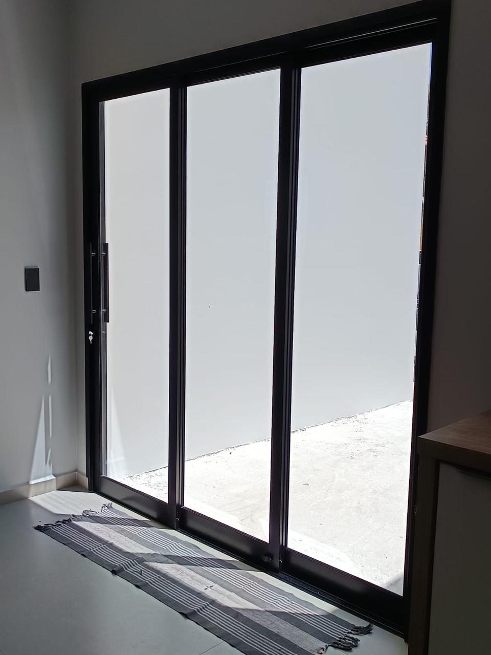 Porta de correr de alumínio com perfil escuro instalada em sala