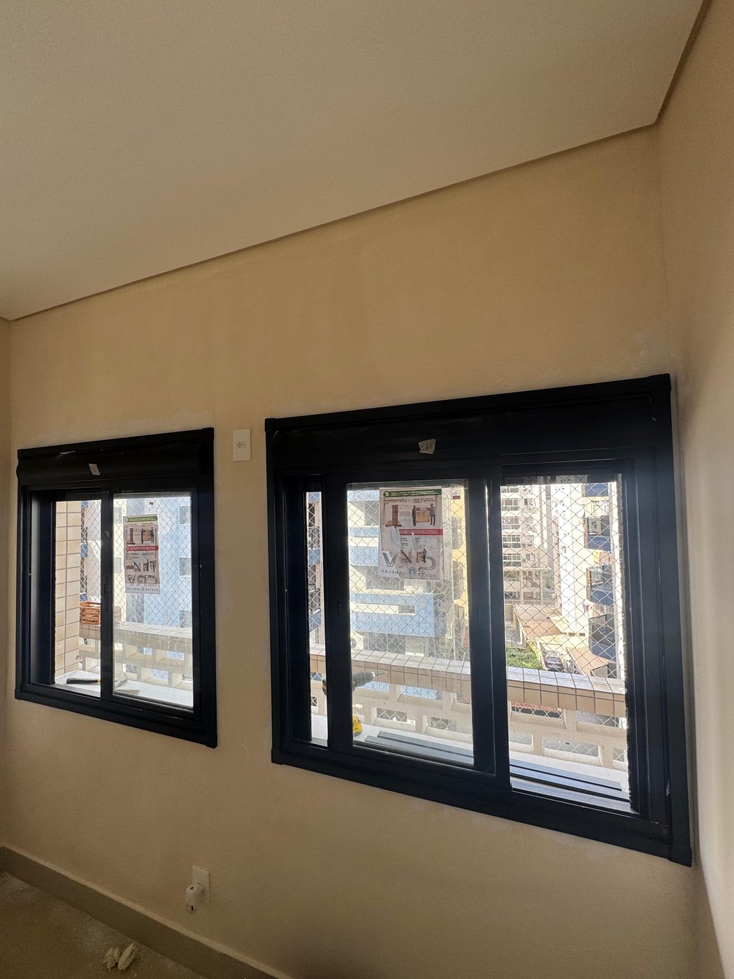 Duas janelas de alumínio com perfil preto instaladas em sala